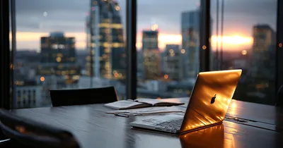 Closed laptop and pitch deck printout on an empty boardroom table at dusk